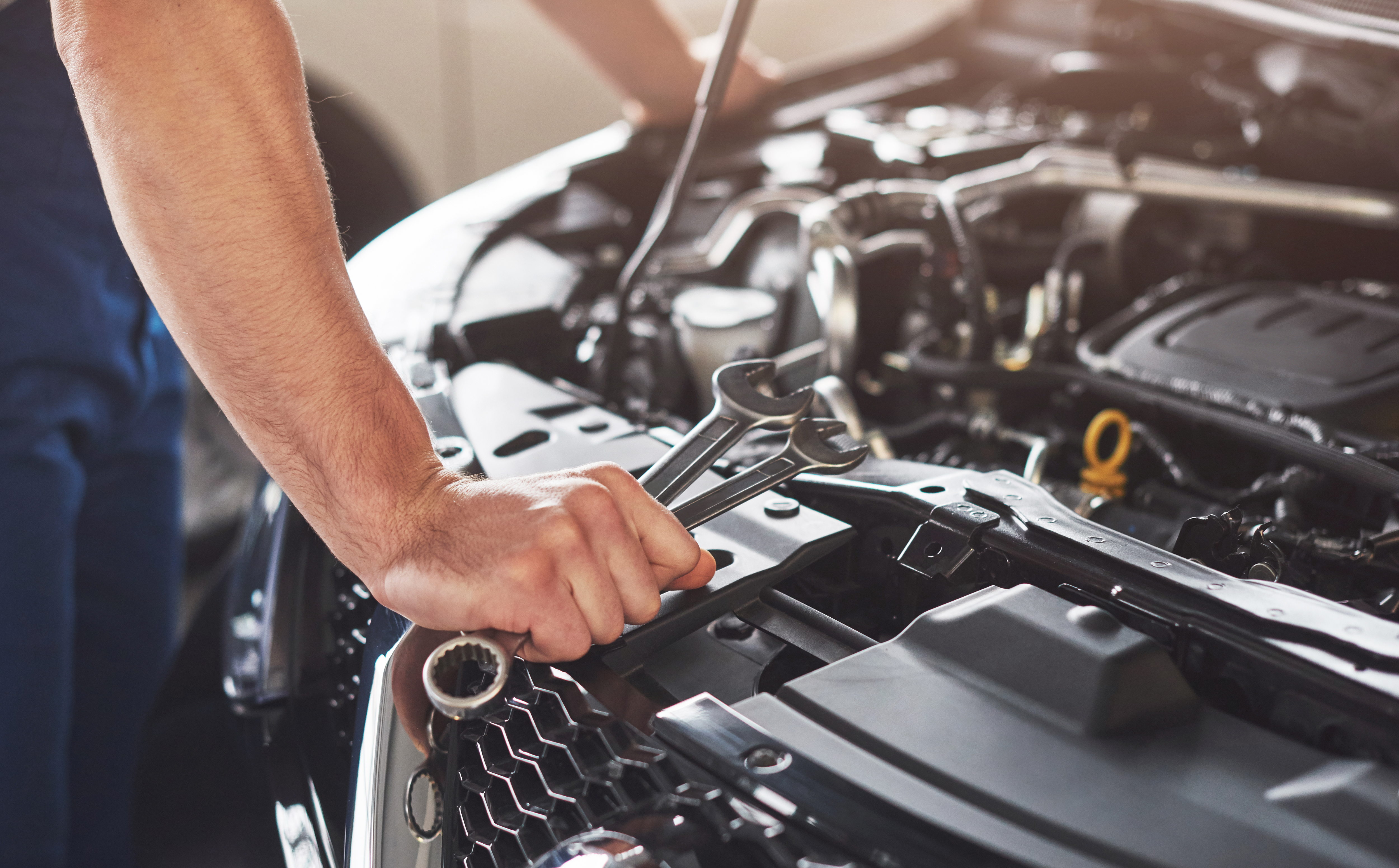 Home picture showing muscular car service worker repairing vehicle